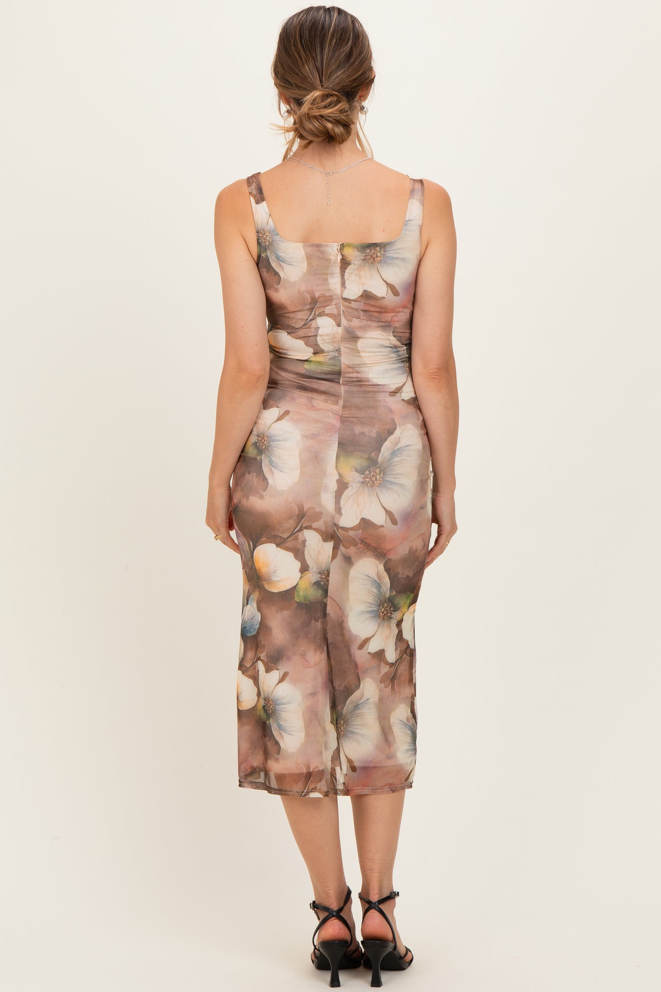 woman wearing a floral print maternity dress with a fitted silhouette, showing the back view