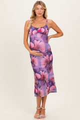 woman wearing a purple floral maternity dress and holding her baby bump