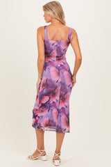 woman wearing a floral purple maternity dress with a fitted bodice and midi length, showing a baby bump from the back