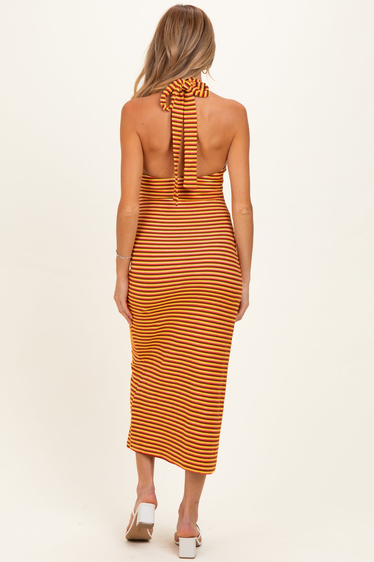woman wearing a striped orange and yellow maternity dress with a halter neck and open back detail