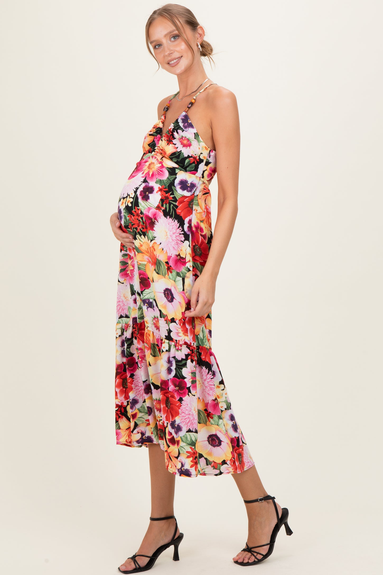 woman wearing a floral print maternity maxi dress with a low neckline and holding her baby bump
