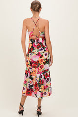 woman wearing a floral print maternity dress with cross-back straps and a tied detail at the back, showing a baby bump