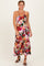woman wearing a floral maxi dress with a halter neckline and strappy back, standing in heels against a neutral background