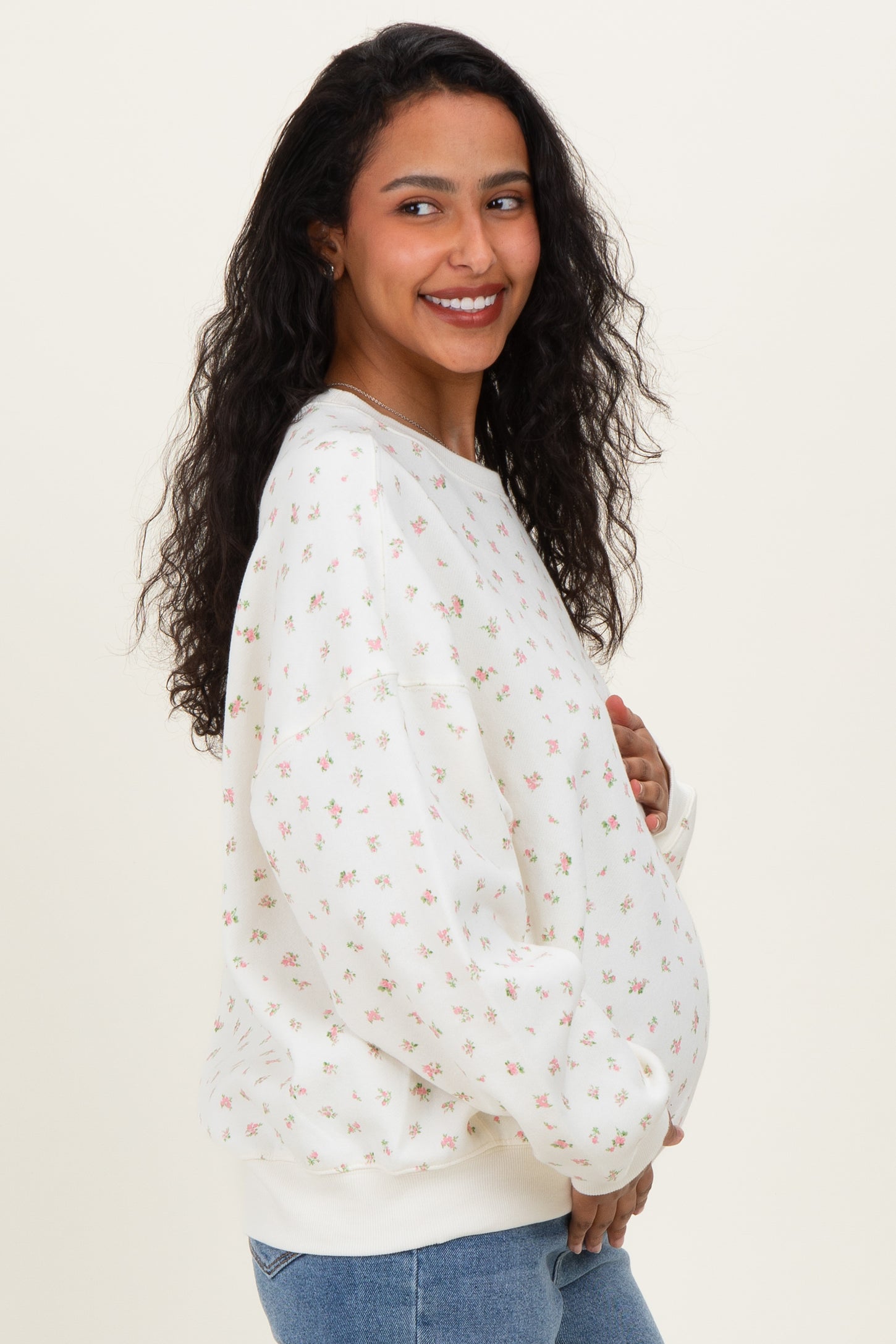 woman wearing a cream floral print maternity sweatshirt and showcasing her baby bump