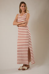 woman wearing a sleeveless red and white striped maxi dress with a side slit and white slide sandals