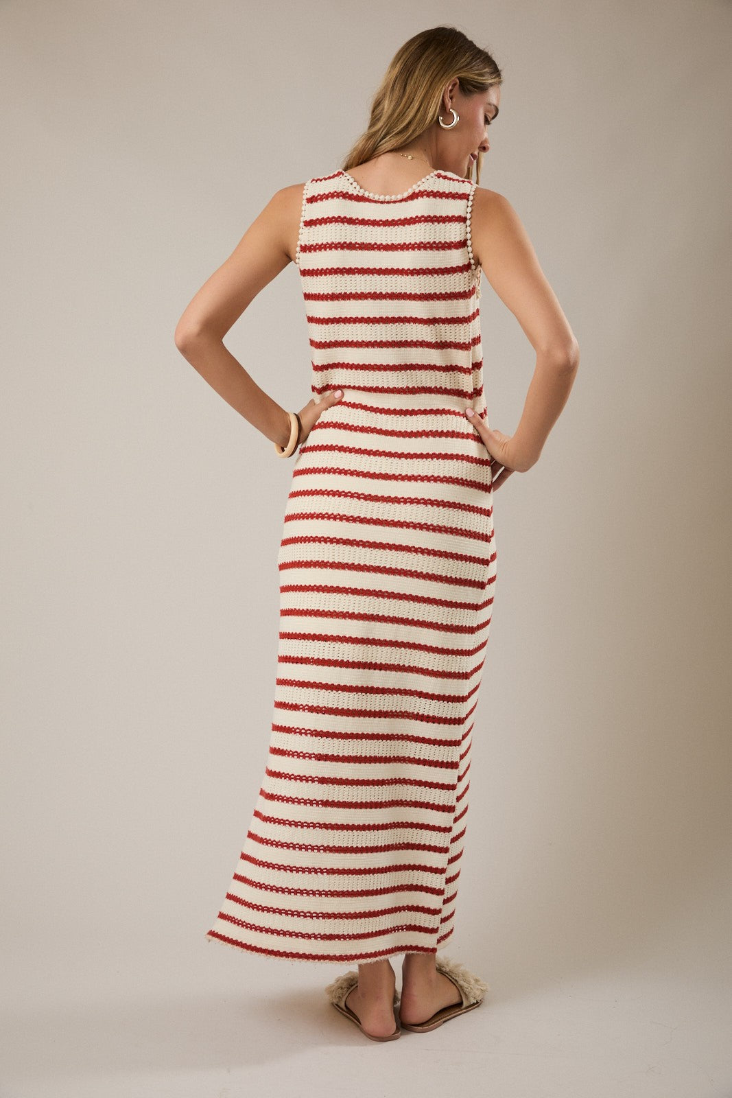 woman wearing a red and white striped sleeveless maxi dress, looking back, with a relaxed fit and side slits