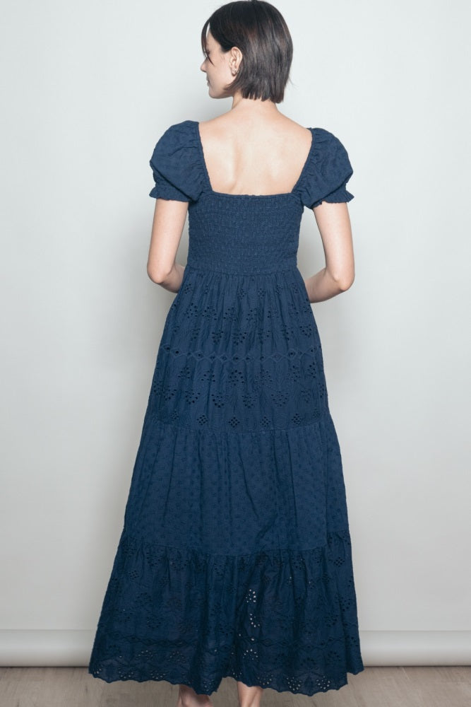 woman wearing a navy blue maxi dress with a smocked bodice and puff sleeves, shown from the back