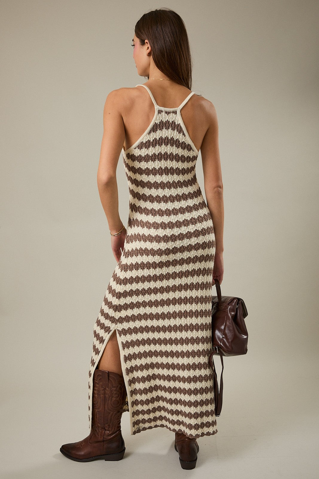 woman wearing a brown and cream patterned maxi dress with a side slit and strappy back, paired with brown cowboy boots