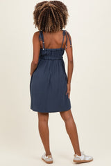 woman wearing a navy blue maternity dress with adjustable tie straps and a smocked back