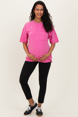 woman wearing a bright pink maternity t-shirt with a pocket and black leggings, holding her baby bump