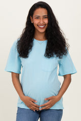 woman wearing a light blue short sleeve maternity top and holding her baby bump