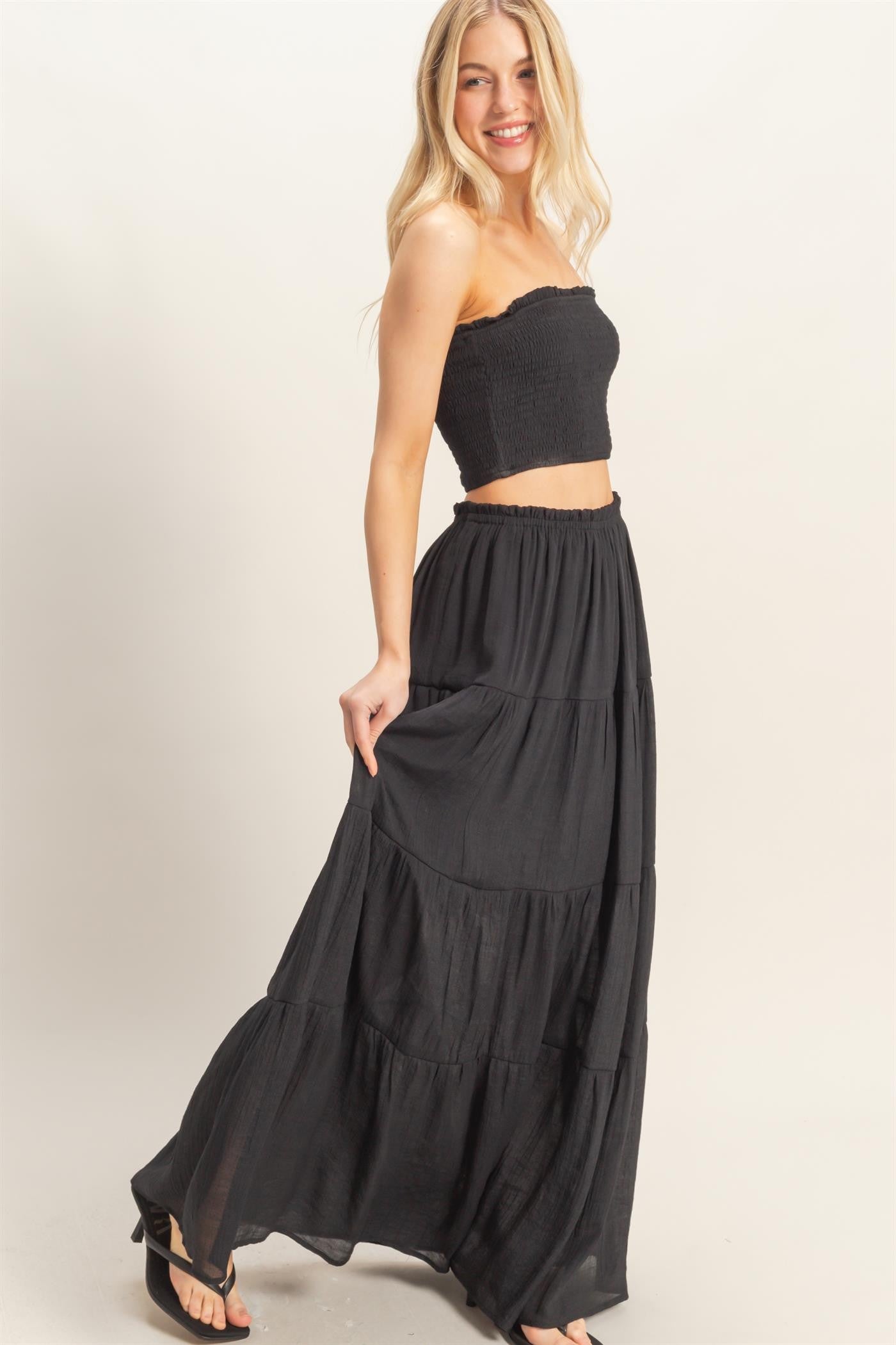 woman wearing a black strapless smocked top and a matching tiered maxi skirt