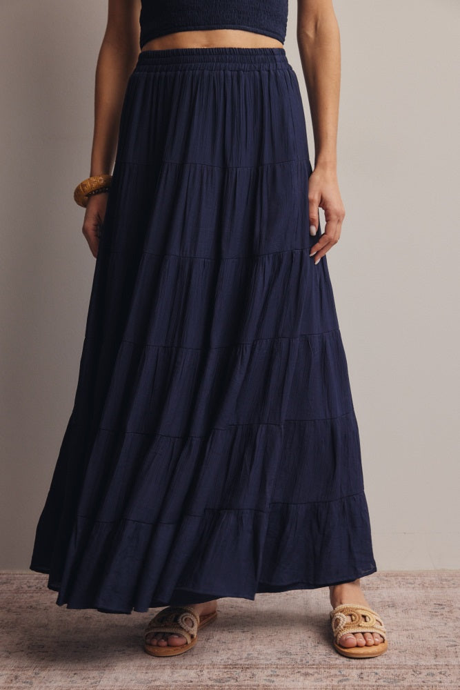 woman wearing a navy blue tiered maxi skirt with an elastic waistband and sandals