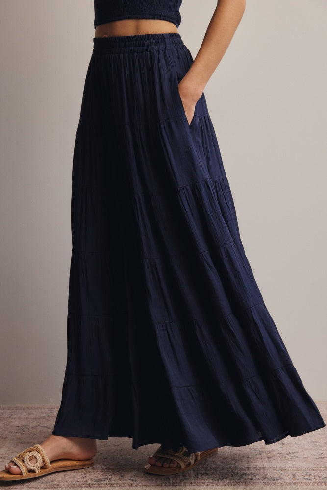 woman wearing a navy blue tiered maxi skirt with pockets and an elastic waistband
