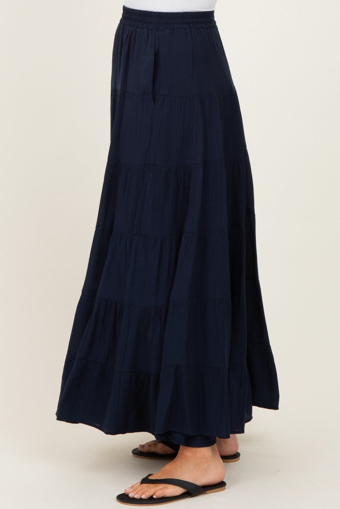 woman wearing a navy blue tiered maxi skirt with an elastic waistband and side pockets