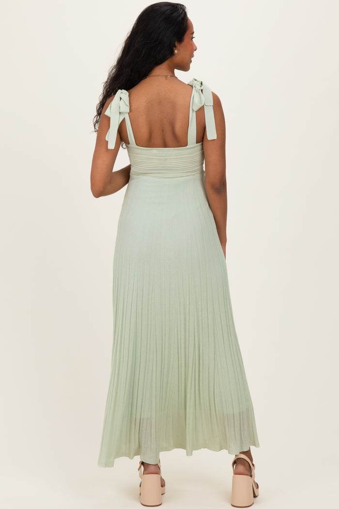 woman wearing a light green maternity maxi dress with tie straps and a fitted bodice, showing the back view