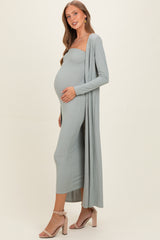 woman wearing a mint green ribbed maternity dress with a long cardigan and displaying her baby bump