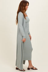 woman wearing a light green ribbed midi dress with a matching long cardigan and brown sandals