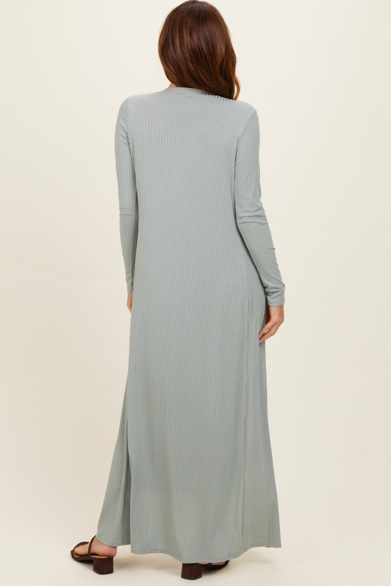 woman wearing a long sage green ribbed maxi dress with long sleeves and side slits