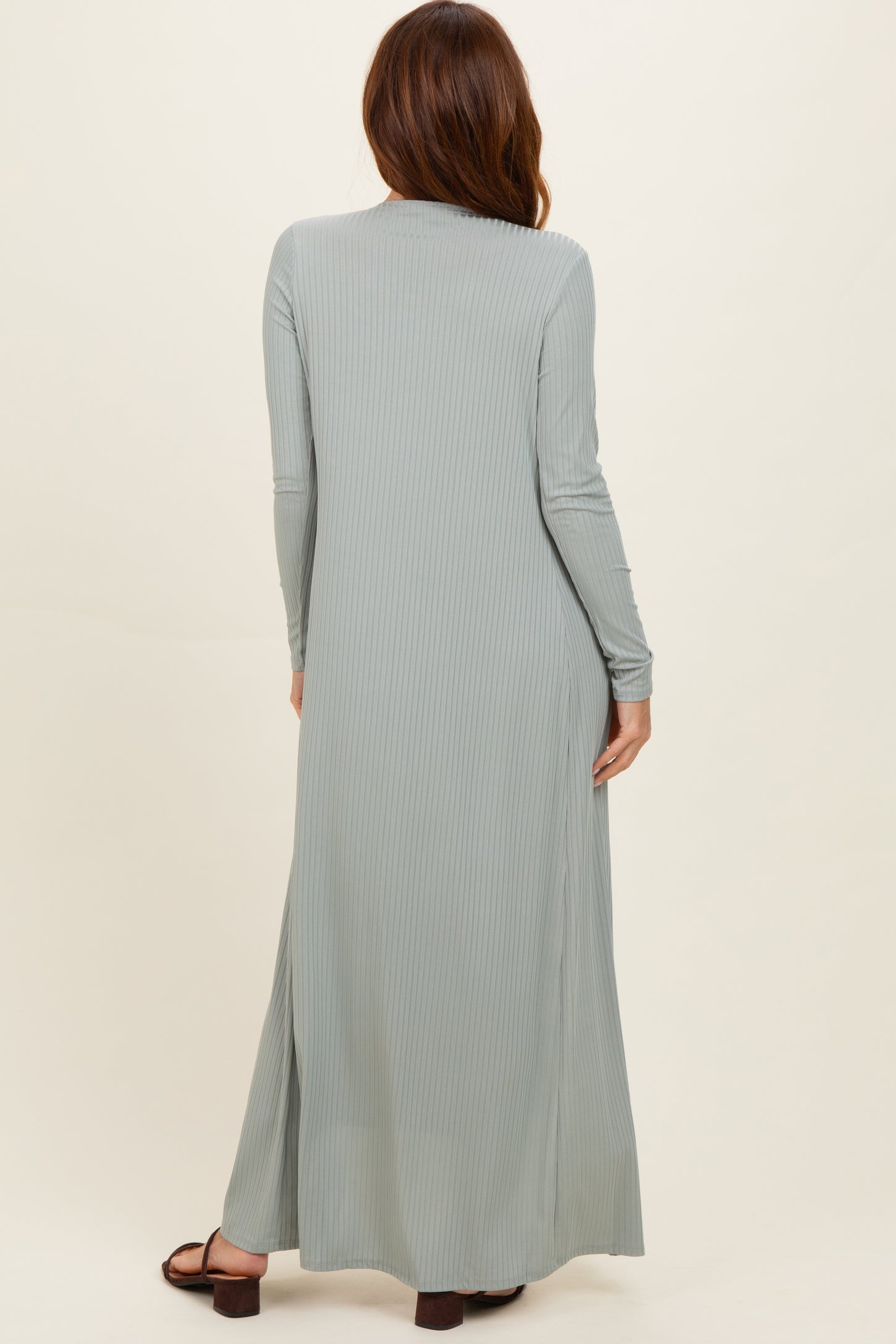 woman wearing a long sage green ribbed maxi dress with long sleeves and side slits