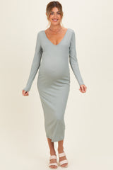 woman wearing a light green long sleeve ribbed maternity dress and showing her baby bump