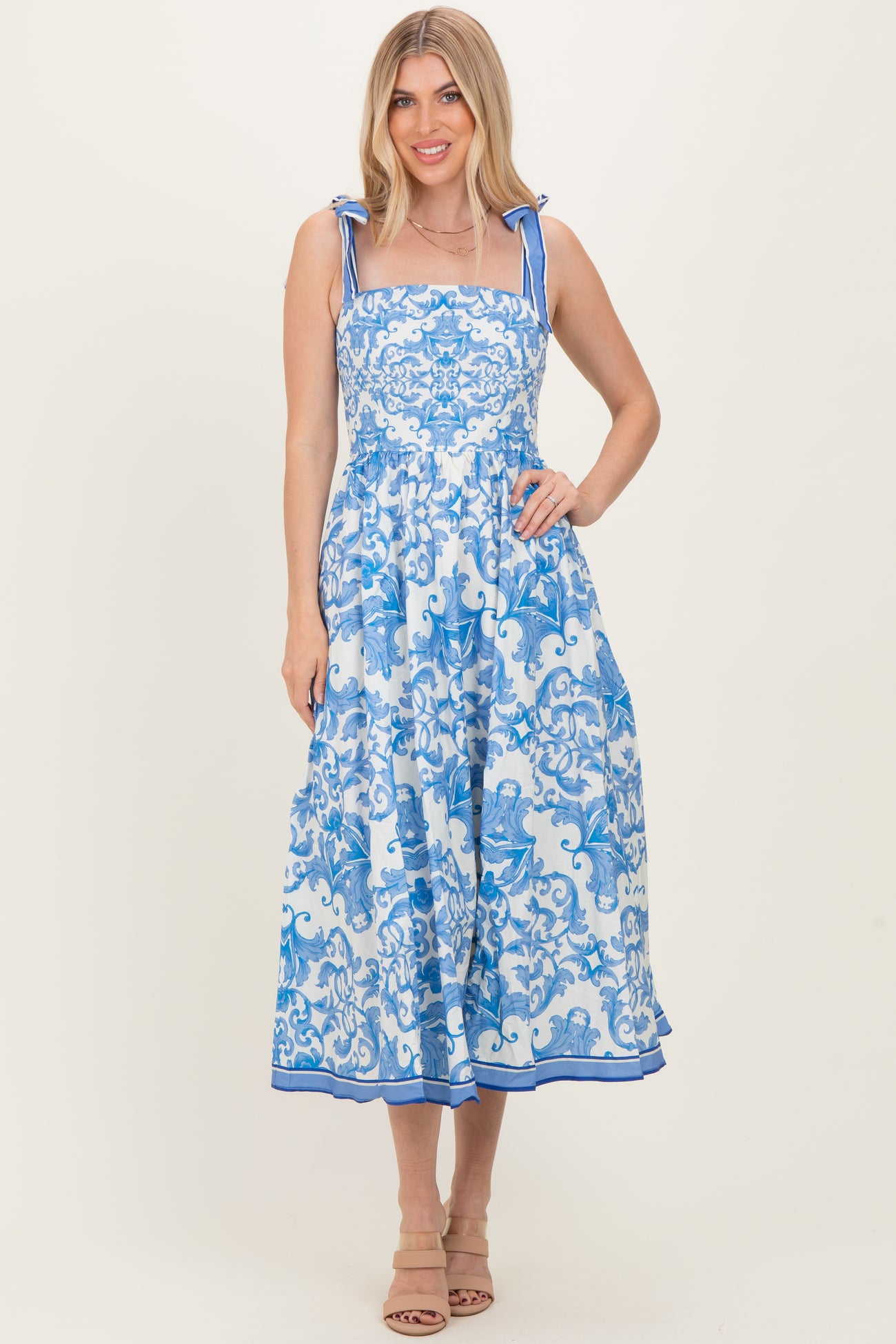 woman wearing a blue and white floral midi dress with tie straps and a flowing skirt