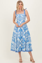 woman wearing a blue and white floral midi dress with tie straps and a fitted bodice