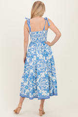 woman wearing a blue and white patterned midi dress with adjustable tie straps and a smocked back