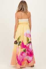 woman wearing a strapless yellow maternity maxi dress with pink floral print on the back