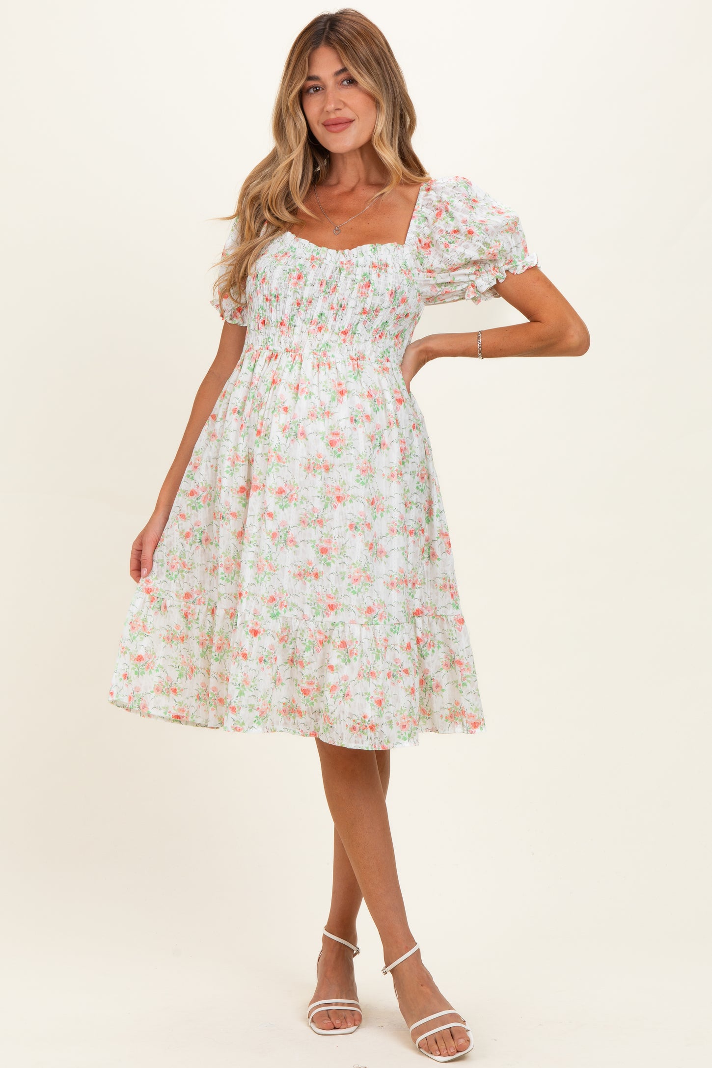 woman wearing a white floral maternity dress with puff sleeves and a fitted bodice, showcasing a baby bump