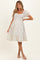 woman wearing a white floral maternity dress with puff sleeves and a fitted bodice, showcasing a baby bump