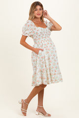 woman wearing a floral print maternity dress with puff sleeves and pockets, showcasing a baby bump
