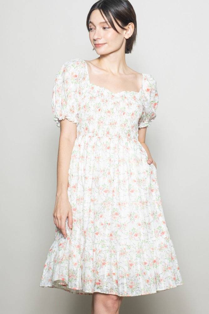 woman wearing a floral puff sleeve dress with a square neckline and pockets, featuring a tiered skirt