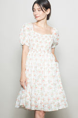 woman wearing a floral puff sleeve dress with a square neckline and pockets, featuring a tiered skirt