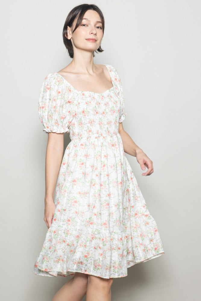 woman wearing a white floral puff sleeve dress with a square neckline and smocked bodice