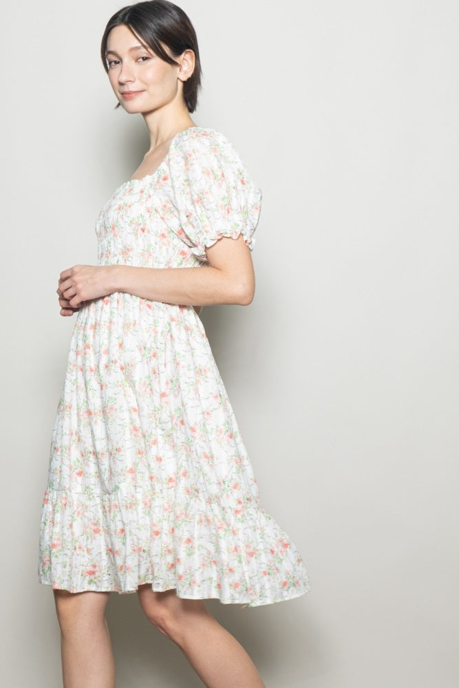 woman wearing a floral print white puff sleeve dress with a smocked bodice and flowing skirt