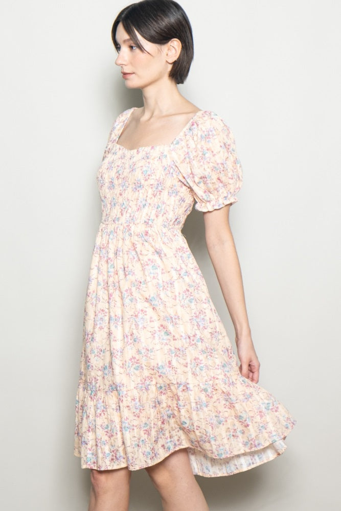 woman wearing a floral short puff sleeve dress with a square neckline and a tiered hem