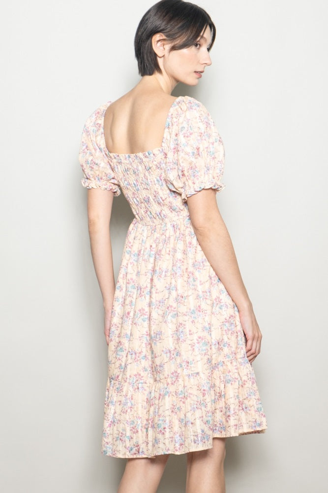 woman wearing a pastel floral puff sleeve dress with a square neckline and gathered back detail