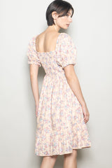 woman wearing a pastel floral puff sleeve dress with a square neckline and gathered back detail