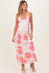 woman wearing a floral pink maternity maxi dress with a halter neck, styled elegantly over her baby bump