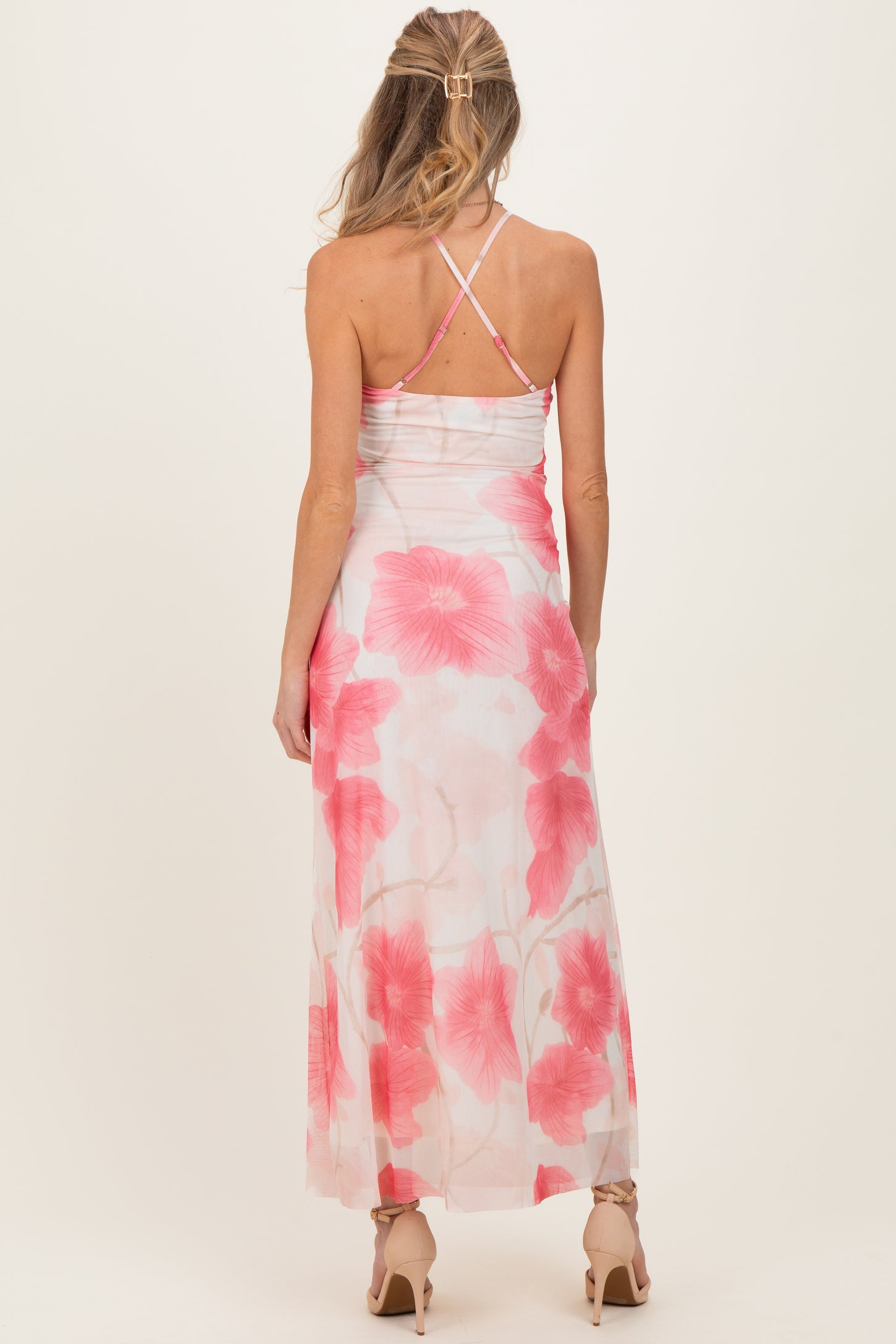 woman wearing a floral maternity maxi dress with pink flowers, showing the back and crisscross straps