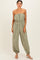 woman wearing a green strapless jumpsuit with a drawstring waist and tapered legs, styled with white sandals