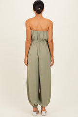woman wearing astrapless olive green jumpsuit with a loose fit and elastic waistband, viewed from the back