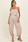 woman wearing a beige strapless maternity jumpsuit with a drawstring waist and elastic cuffs, showing her baby bump