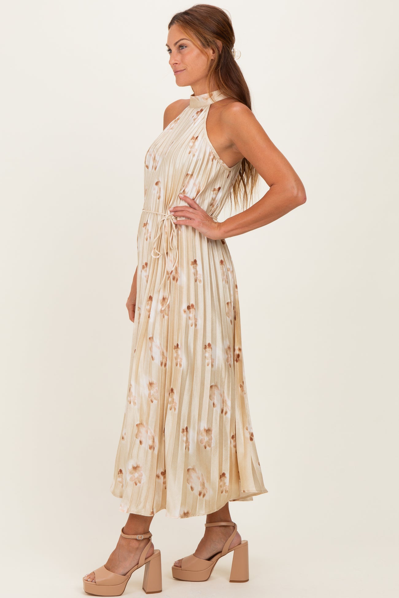 woman wearing a beige floral print maxi dress with a halter neck and drawstring waist
