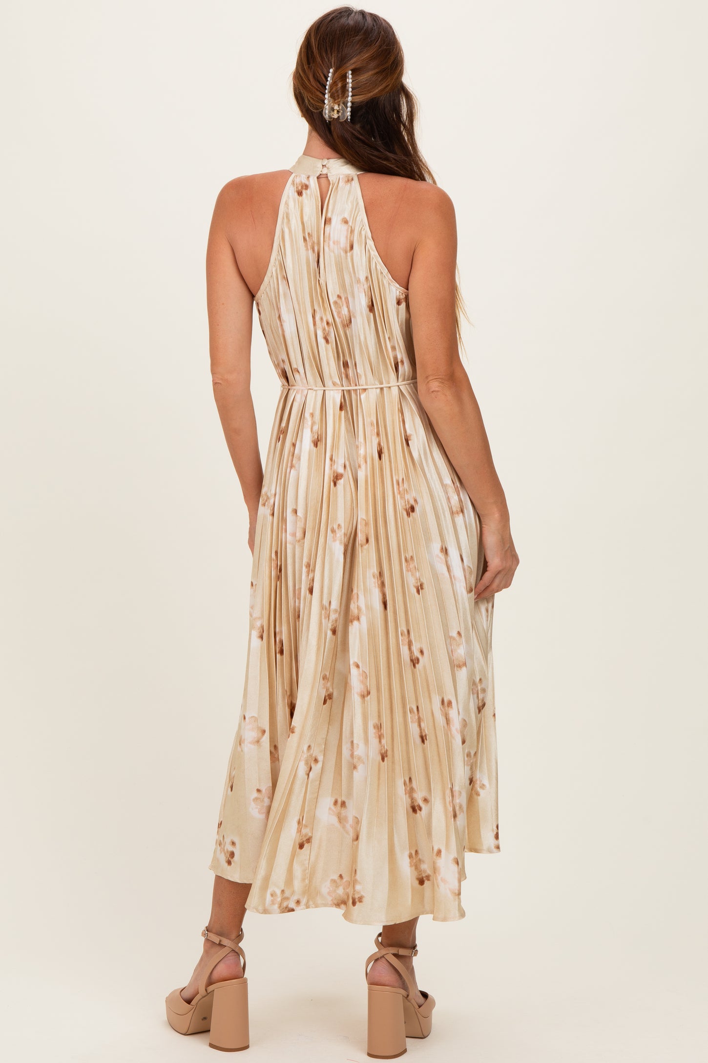 woman wearing a back view of a floral-print midi dress with a halter neck and pleated fabric