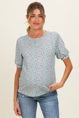 woman wearing a light blue floral maternity top and showing her baby bump