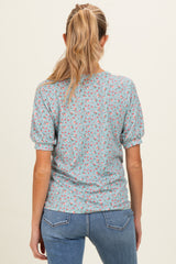 woman wearing a light blue short sleeve maternity top with a floral print, showing the back view