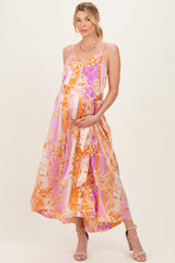 woman wearing a colorful floral maternity maxi dress and holding her baby bump