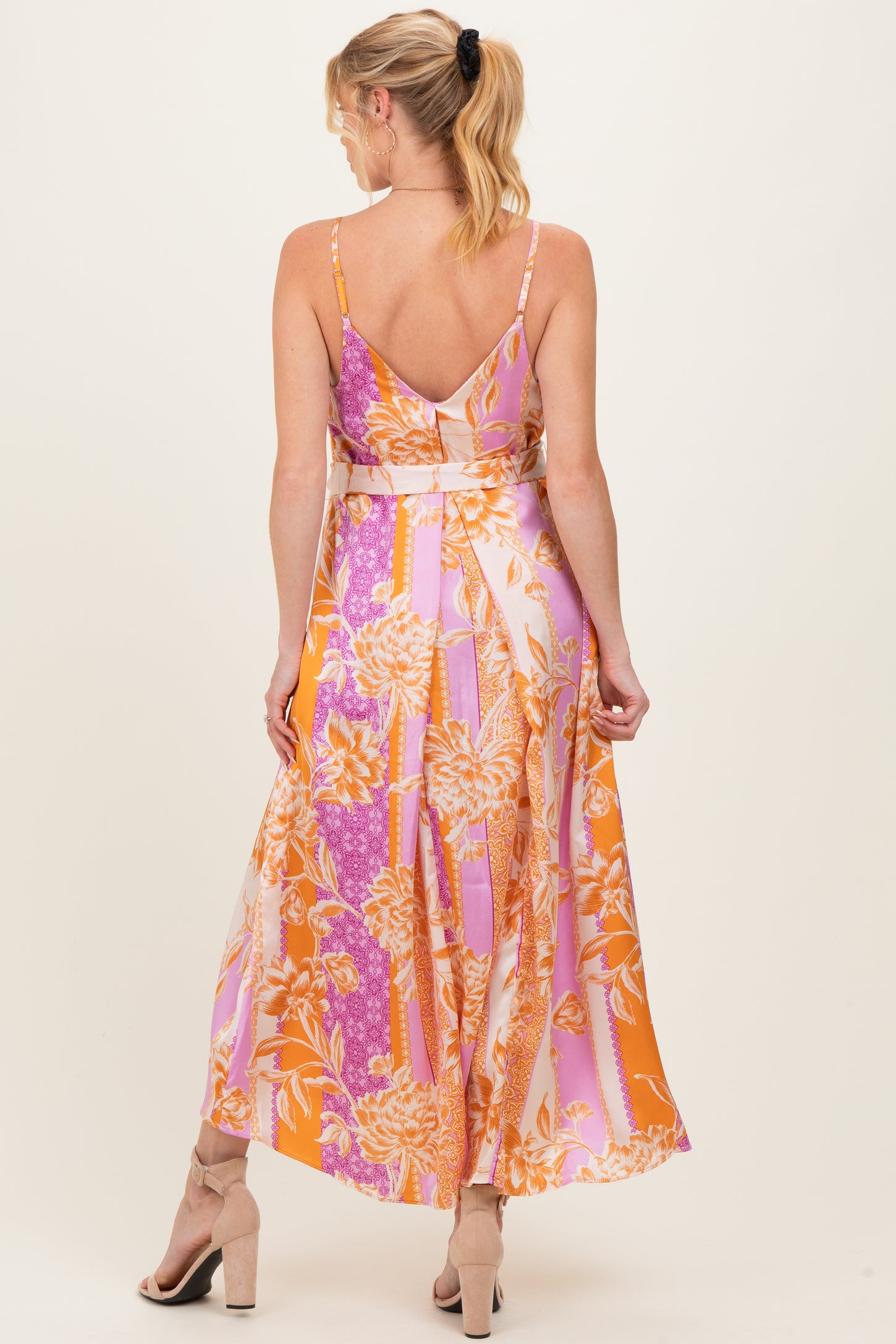 woman wearing a colorful floral print maternity maxi dress with thin straps and an open back